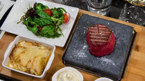 Sallad, ugnspotatis och en raw steak upplagd på planka
