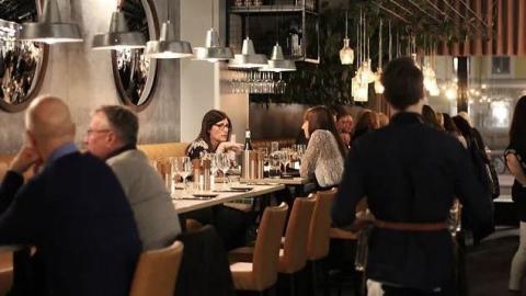 Olika sällskap sitter vid olika bord på en restaurang inomhus