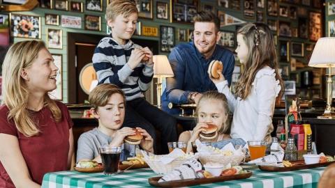Glad familj äter burgare tillsammans på restaurang 