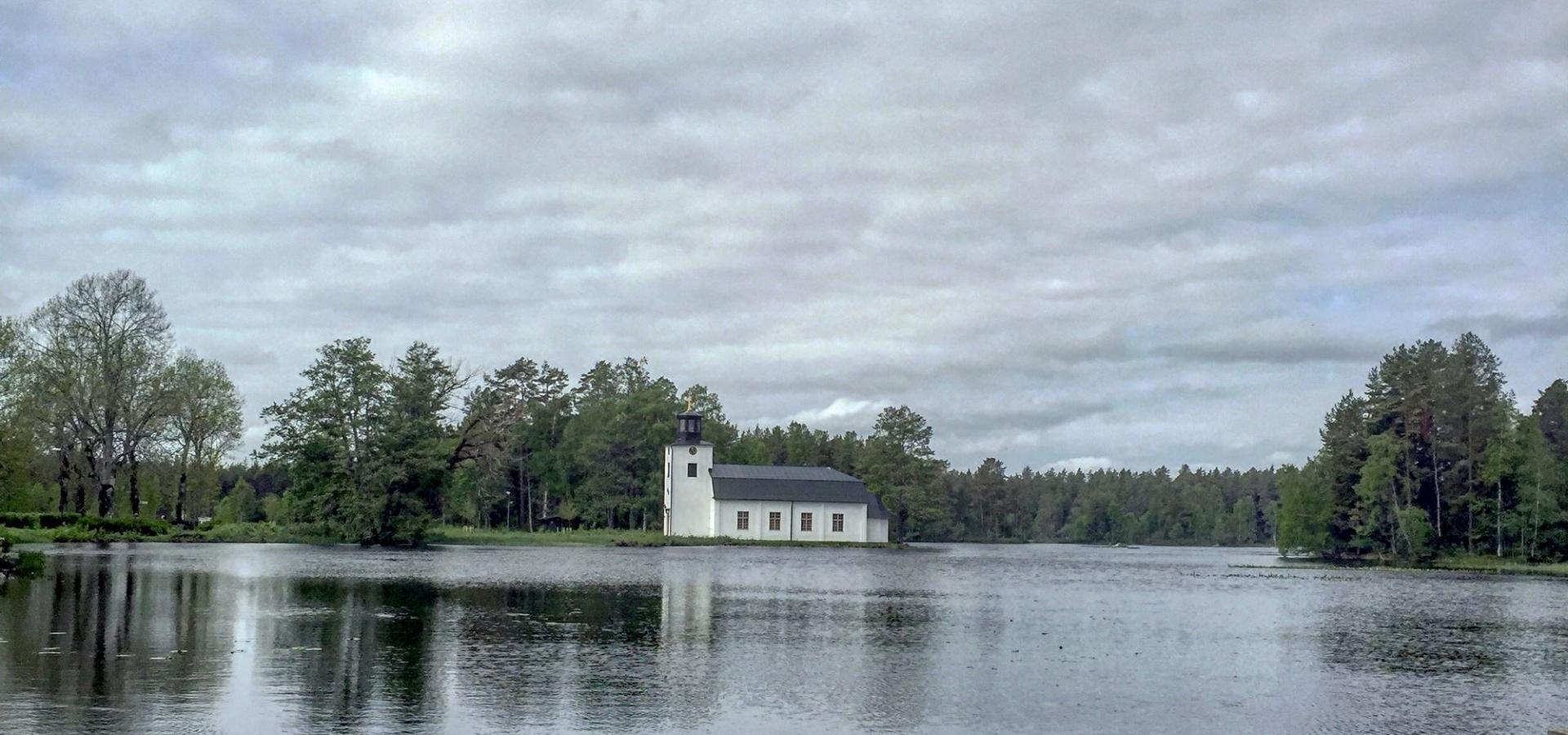 Oslättfors kyrka med båt i förgrunden. Foto Elena Vilhelmsson.