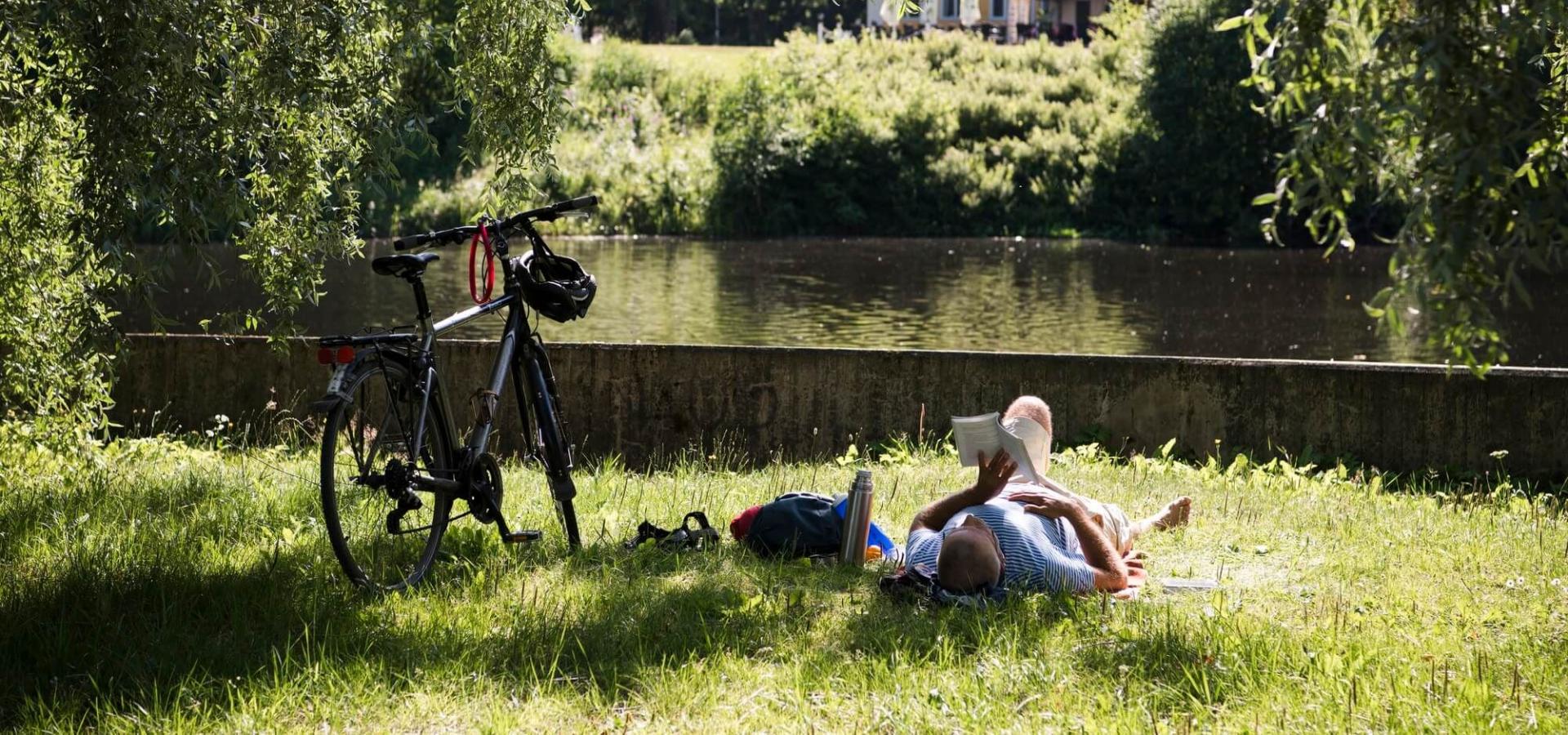 Boulognerskogen vid Stora Vall. Man ligger och läser i gräset. Foto Daniel Bernstål.