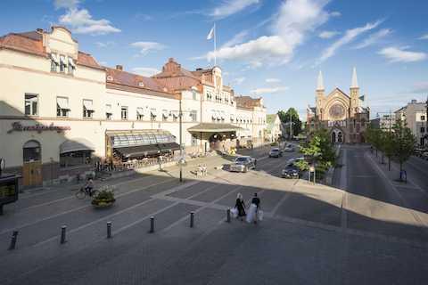Centralstationen i Gävle. En ljus stenbyggnad som halvt är täckt av skugga och halvt badar i sol.