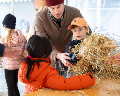 Barn och vuxen bygger halmbock inomhus i ett tält - Foto Gävle City