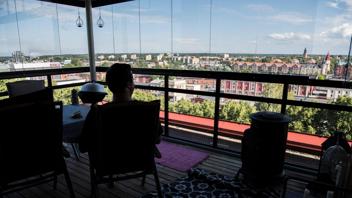 En person sitter i förgrunden på en balkong i Gävle