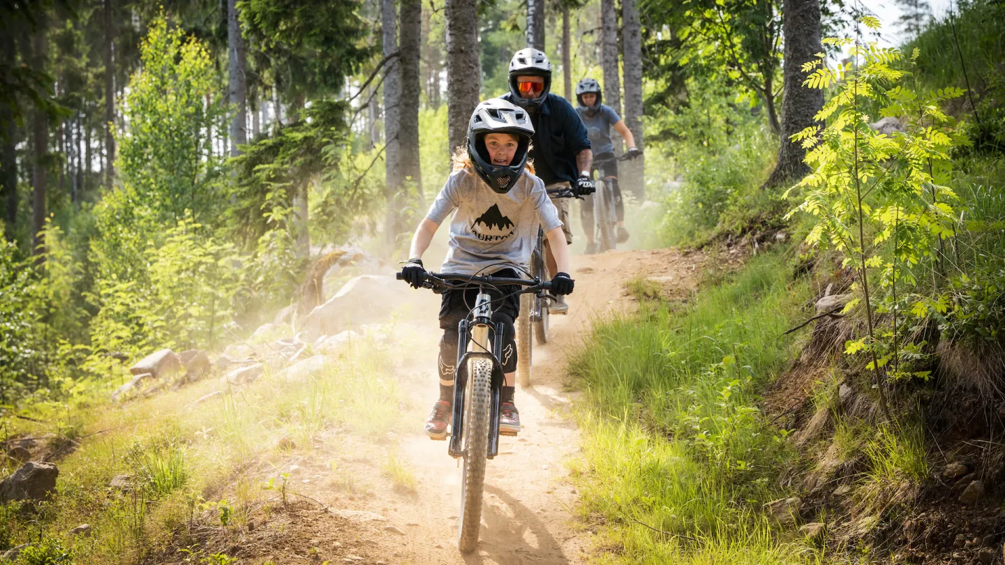 Barn på cykel nedför en stig i skogen