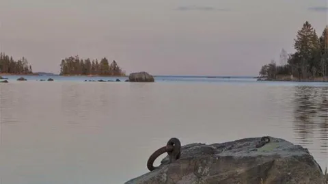 Sten i vatten med järnring i förgrunden till utsikten mot havet
