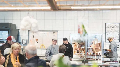 Dam och herre socialiserar och personal pratar över disk med kvinna i Diléns Saluhall