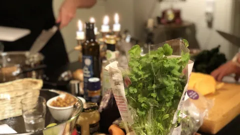 A chef cooking in the background. In front of a table with ingredients such as salad for spices and drinks