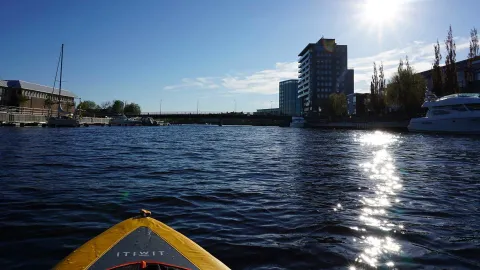 Göran på en kajak som glider genom stilla vatten med motljus