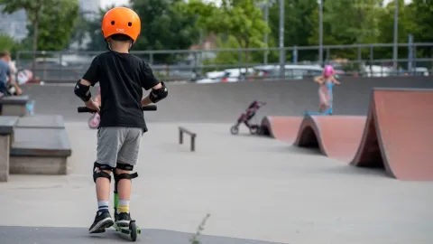 Pojke på en sparkcykel bakifrån