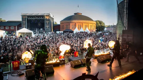 Outdoor concert with a large crowd in front of the stage