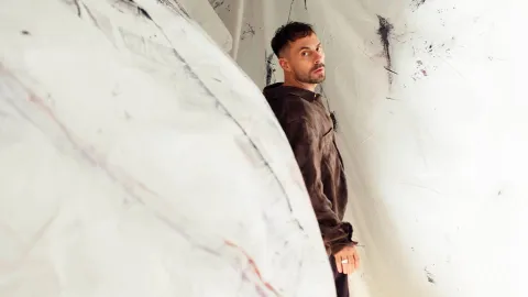 Artisten Oskar Linnros vänder sig och tittar i kameran