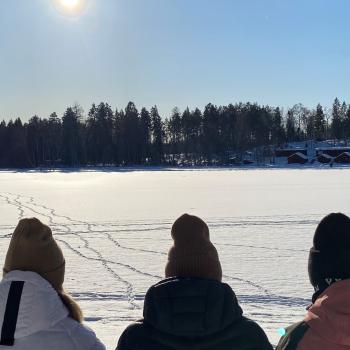 Tre personer vilar i vintersolen vid isbelagda Högbo sjön