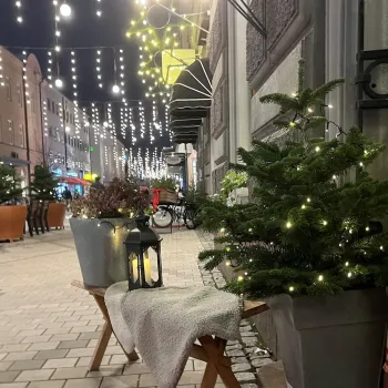 Kvällsbild med en halmbock, gran och bänk med en lykta