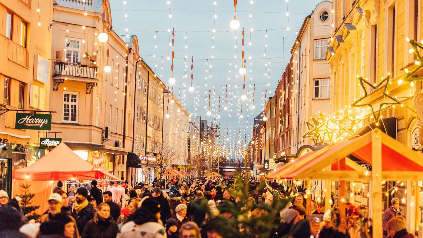 Julmarknad på gågata en kväll med massor av folk och julbelysning